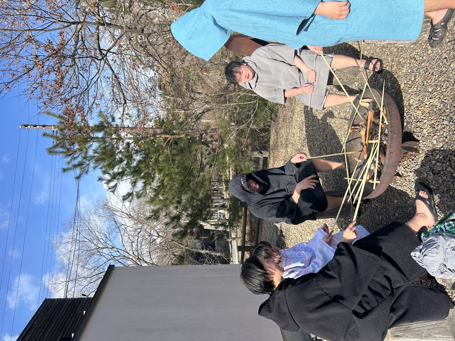 焚き火を囲み、ソーセージを炙る